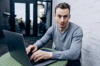 Gri ceketli adam, bilişim uzmanı, dizüstü bilgisayarda oturuyor ve çalışıyor.