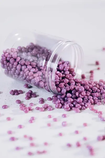 Purple eyebrow wax in the form of granules is scattered on the table. Cosmetology, eyebrow specialist