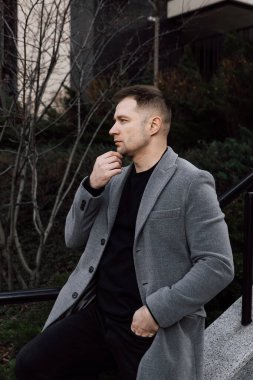 Gri ceketli yakışıklı sokakta yürüyor.