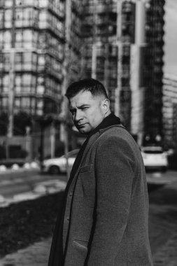 Gri ceketli yakışıklı sokakta yürüyor.