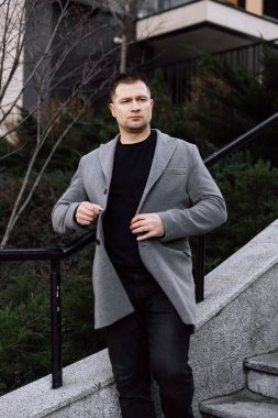Gri ceketli yakışıklı sokakta yürüyor.