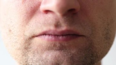 Adamın ağzı kamera karşısında buruşuyor. Tıraşsız bir yüz.