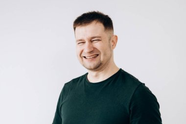 Yeşil tişörtlü neşeli Avrupalı genç adam kameranın önünde duygularını gösteriyor.