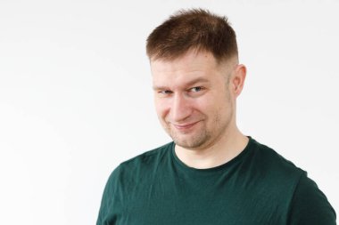 Yeşil tişörtlü neşeli Avrupalı genç adam kameranın önünde duygularını gösteriyor.