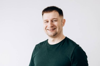 Yeşil tişörtlü neşeli Avrupalı genç adam kameranın önünde duygularını gösteriyor.