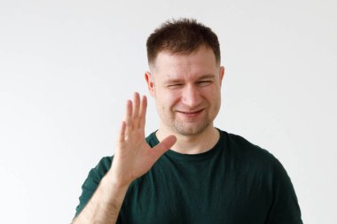 Yeşil tişörtlü neşeli Avrupalı genç adam kameranın önünde duygularını gösteriyor.