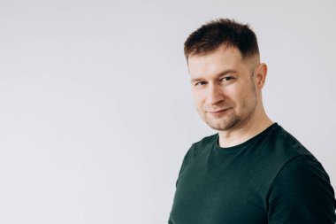 Yeşil tişörtlü neşeli Avrupalı genç adam kameranın önünde duygularını gösteriyor.