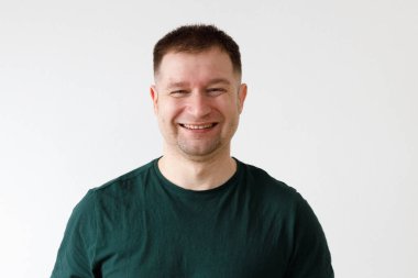 Yeşil tişörtlü neşeli Avrupalı genç adam kameranın önünde duygularını gösteriyor.