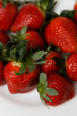 Sulu kırmızı çilekler beyaz çay tabağının üzerinde.