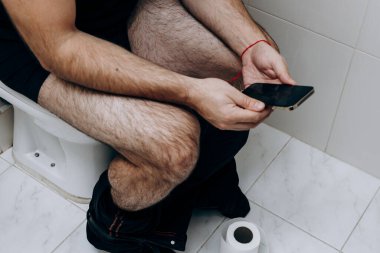 Adam elinde telefonla tuvalette oturuyordu. Adamın sabah rutini.