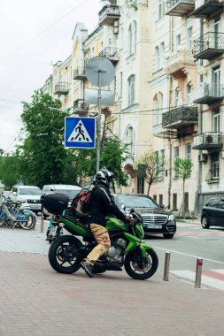 Yeşil motosikletli motorcu şehirde geziyor.