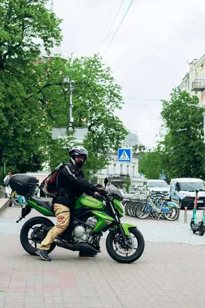 Biker on green motorcycle rides through city