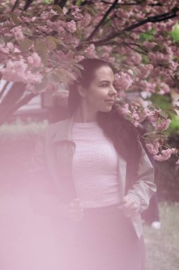 Çiçek açan ağaçta güzel bir kızın fotoğrafı çekiliyor.