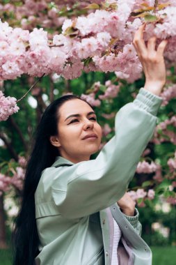 Çiçek açan ağaçta güzel bir kızın fotoğrafı çekiliyor.