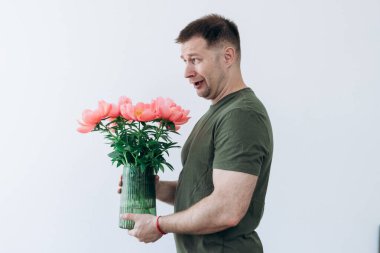 Adamın elinde şakayık vazosu var.