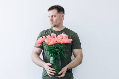 Adamın elinde şakayık vazosu var.