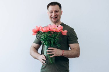 Adamın elinde şakayık vazosu var.