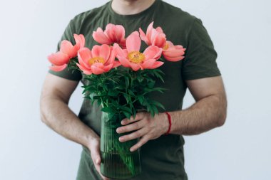 Adamın elinde şakayık vazosu var.