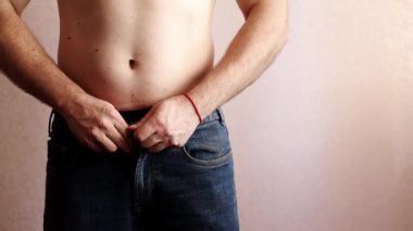 İnsan düğmelerini açar ve pantolonunu çıkartır ve bacaklarından aşağı çeker.