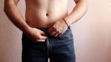 İnsan düğmelerini açar ve pantolonunu çıkartır ve bacaklarından aşağı çeker.