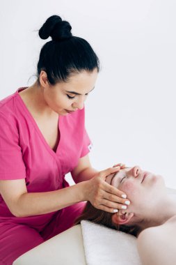 Pembe üniformalı kız kadınlara masaj yapıyor. Sırt egzersizleri, spa tedavileri