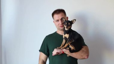 Erkeksi adam kucağında küçük bir Chihuahua köpeği tutuyor. Efendi ve evcil hayvan