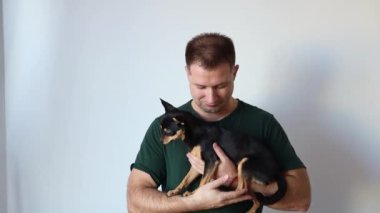 Erkeksi adam kucağında küçük bir Chihuahua köpeği tutuyor. Efendi ve evcil hayvan