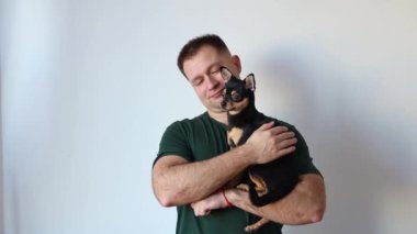 Erkeksi adam kucağında küçük bir Chihuahua köpeği tutuyor. Efendi ve evcil hayvan