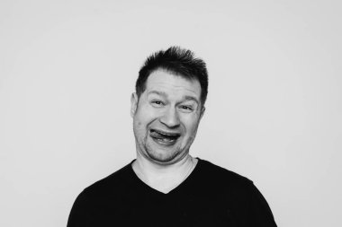 Siyah tişörtlü bir adam etrafta dolanıyor ve kamerada kıvranıyor.