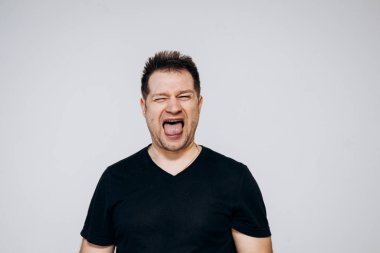 Siyah tişörtlü bir adam etrafta dolanıyor ve kamerada kıvranıyor.