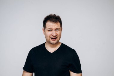 Siyah tişörtlü bir adam etrafta dolanıyor ve kamerada kıvranıyor.