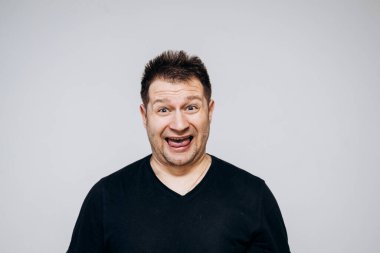 Siyah tişörtlü bir adam etrafta dolanıyor ve kamerada kıvranıyor.