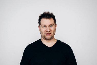 Siyah tişörtlü bir adam etrafta dolanıyor ve kamerada kıvranıyor.