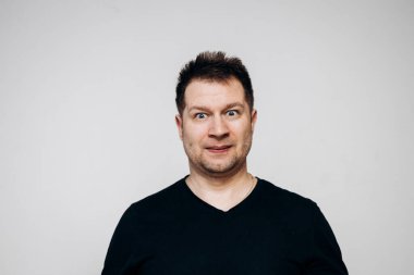 Siyah tişörtlü bir adam etrafta dolanıyor ve kamerada kıvranıyor.