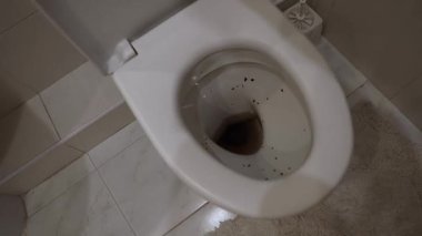 Tuvaleti fırçayla temizleyen adam.