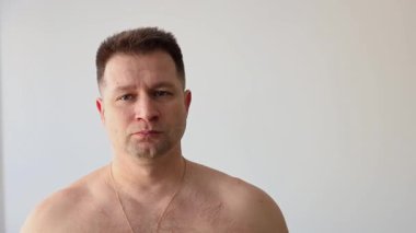 Genç şişirilmiş adam kaslarını gösteriyor. Vücut geliştirici kollarıyla poz verir.