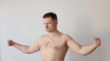 Genç şişirilmiş adam kaslarını gösteriyor. Vücut geliştirici kollarıyla poz verir.