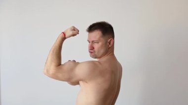 Genç şişirilmiş adam kaslarını gösteriyor. Vücut geliştirici kollarıyla poz verir.
