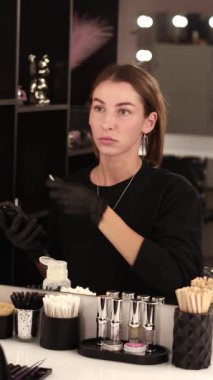 Makyöz işyeri aynanın önünde kaşlarını yapıyor.