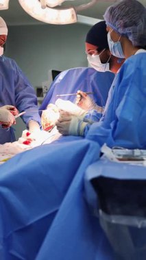 Deneyimli mavi önlüklü cerrahlar hastane ameliyathanesinde askeri bir hastayı ameliyat ederler.