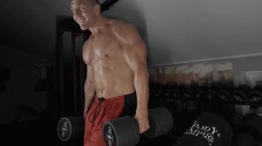 Pompalı adam spor salonunda antrenman yapıyor. Vücut geliştirici dambıl, egzersiz makinesi, halter pompalıyor.