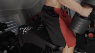 Pompalı adam spor salonunda antrenman yapıyor. Vücut geliştirici dambıl, egzersiz makinesi, halter pompalıyor.
