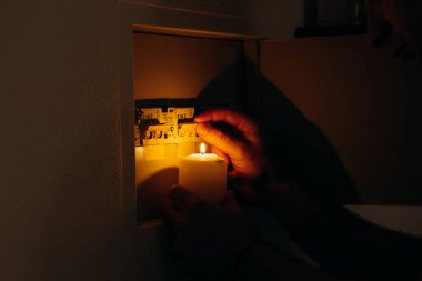 Elektrik kesintisi. Adam bir elektrik panelinin önünde mum tutuyor.