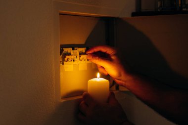 Elektrik kesintisi. Adam bir elektrik panelinin önünde mum tutuyor.