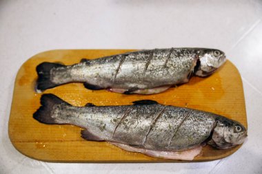 Çiğ alabalık, fırında pişirmek için tahta kesiyor. Balık yemeği tarifleri.