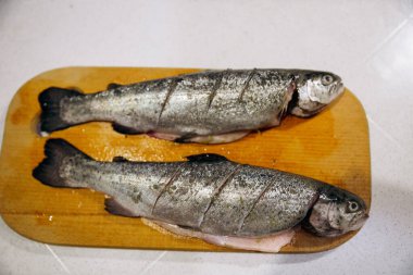 Çiğ alabalık, fırında pişirmek için tahta kesiyor. Balık yemeği tarifleri.