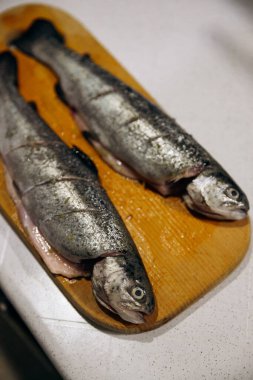 Çiğ alabalık, fırında pişirmek için tahta kesiyor. Balık yemeği tarifleri.