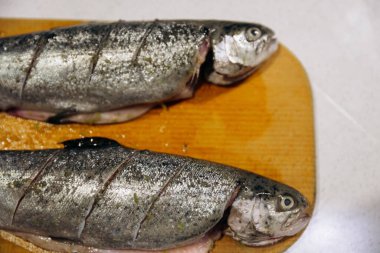 Çiğ alabalık, fırında pişirmek için tahta kesiyor. Balık yemeği tarifleri.