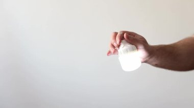 El, titreyen bir enerji tasarrufu ampulünü tutuyor. Elektrik sorunu.