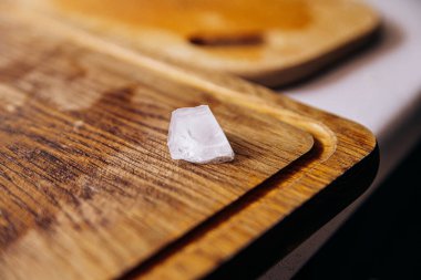 Tahta kokteyl tahtasının üzerinde bir buz parçası var.